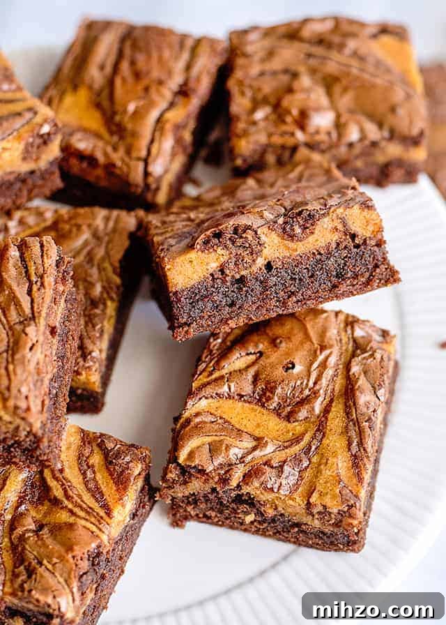 pumpkin brownies on a white plate with one propped up on another showing off the side of the brownie