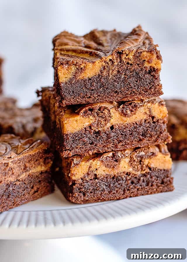 3 pumpkin brownies stacked on a white cake plate