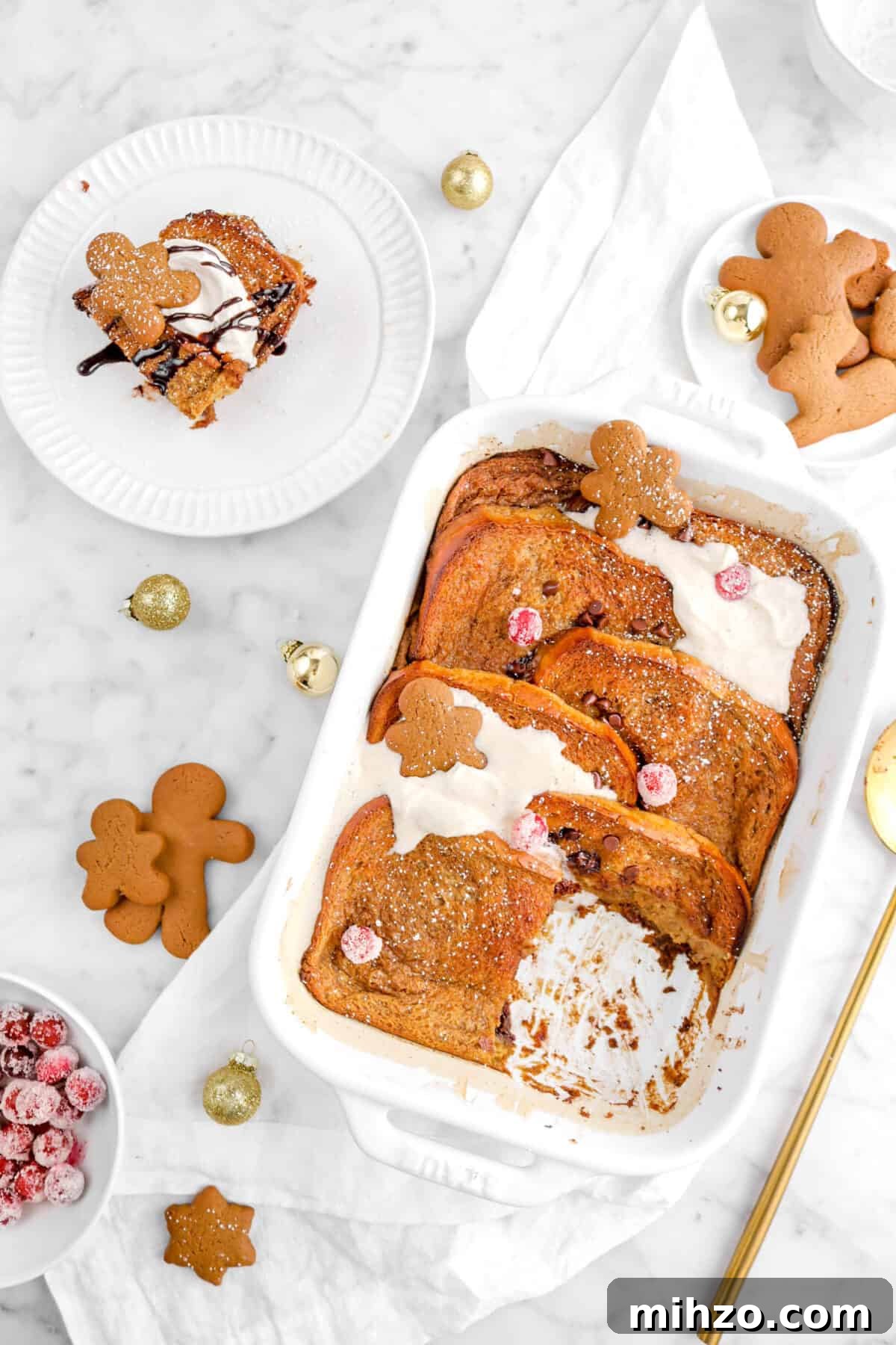 Overnight Gingerbread Chocolate Chip French Toast Bake 6 overhead shot of gingerbread french toast casserole on white napkin with slice of casserole on white plate beside, cookies and mini gold ornaments around