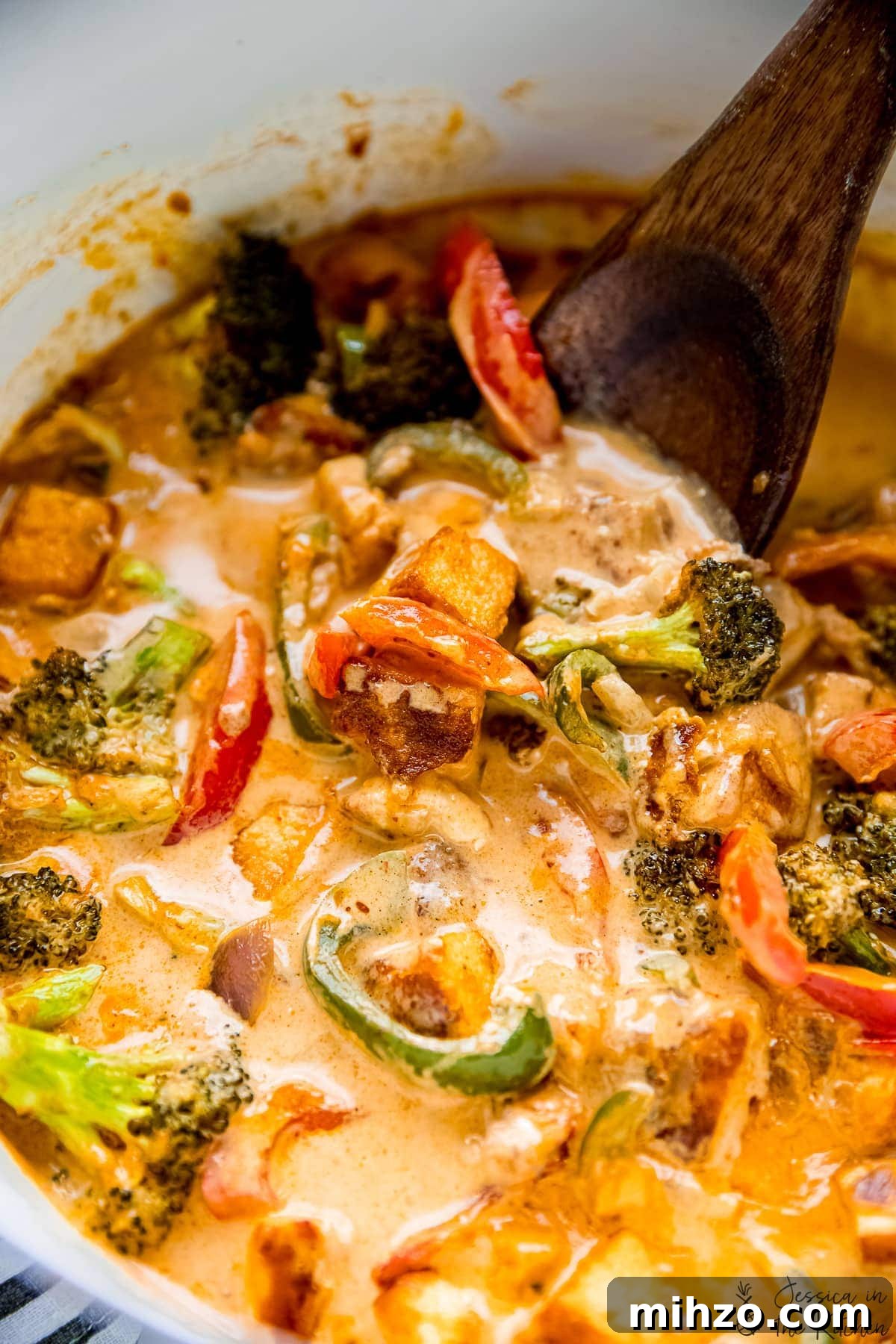 This fragrant Thai red curry is packed with veggies and tender marinated tofu for a satisfying meal. Just add rice or your favorite grain! Wooden spoon stirring Thai red curry