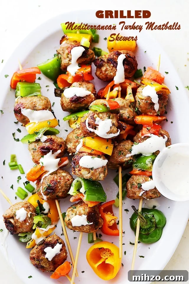 Juicy, flavor-packed turkey meatballs made with feta, olives, and herbs, grilled to perfection and served on skewers with bell peppers. Turkey meatballs and bell pepper slices on skewers, and drizzled with homemade garlic yogurt sauce.