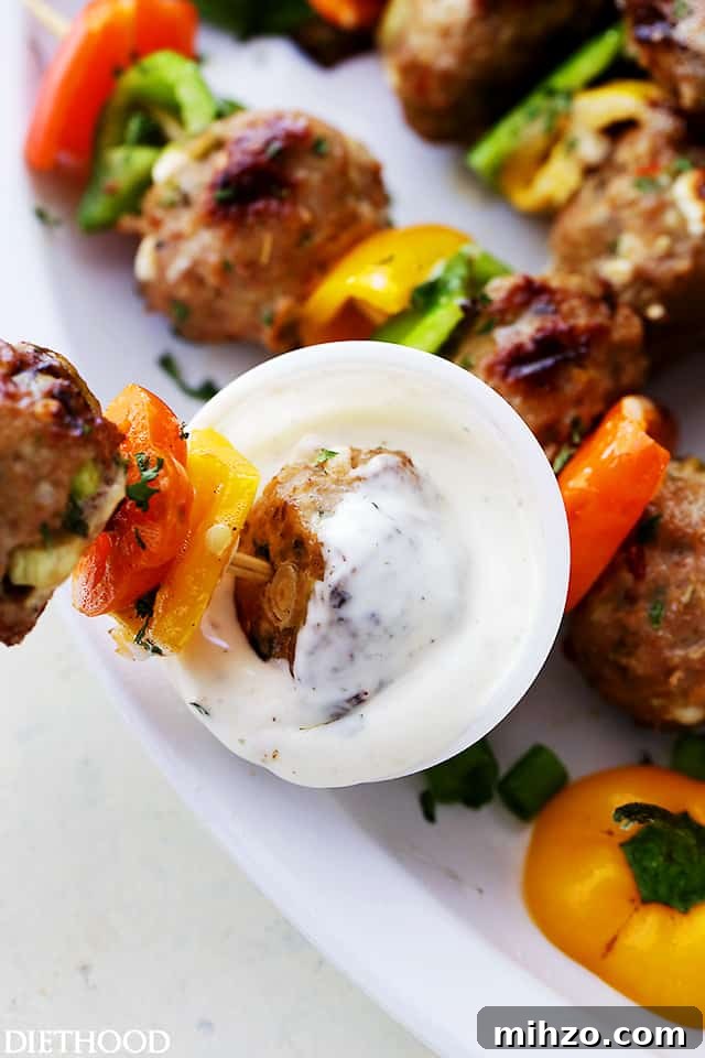 Grilled Turkey Meatball Skewers with Tangy Herb Sauce 6 Dipping a meatball skewer in yogurt sauce.