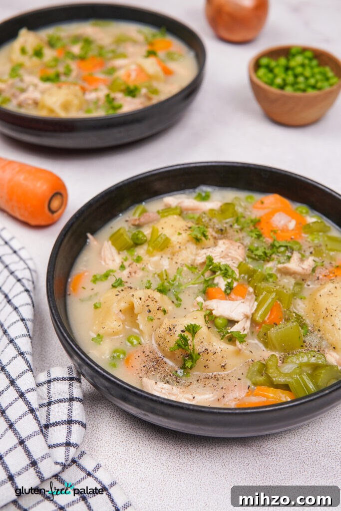 Gluten-Free Soup Dumplings Recipe: How to Make Juicy Xiao Long Bao 3 Side angle view of two black bowls of gluten-free chicken and dumplings soup with carrots, celery, peas, and parsley, next to a carrot and a bowl of peas.