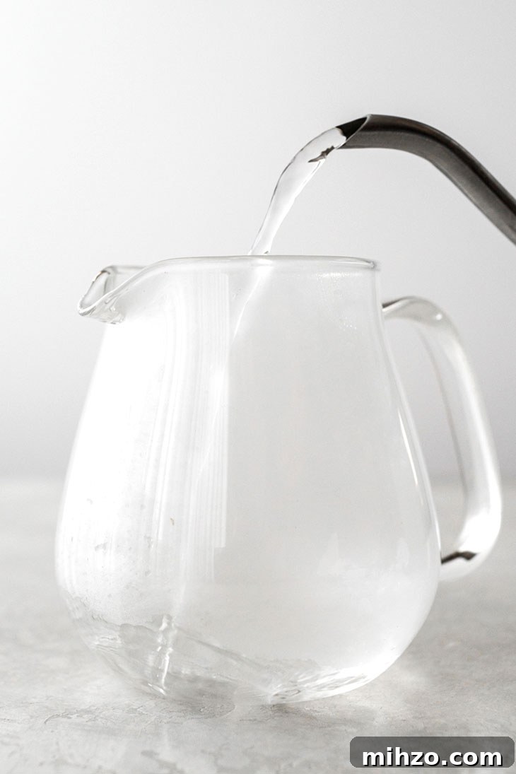 Pouring hot water into a glass teapot.