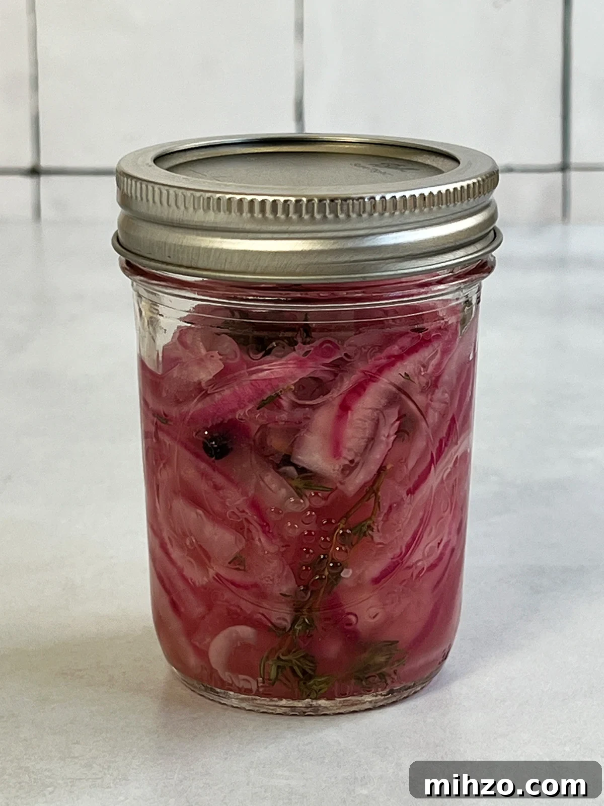 Crisp Pickled Red Onions: Quick Tangy Recipe for Sandwiches & Salads 2 Pickled red onions in a canning jar close up view of some that are ready to eat.