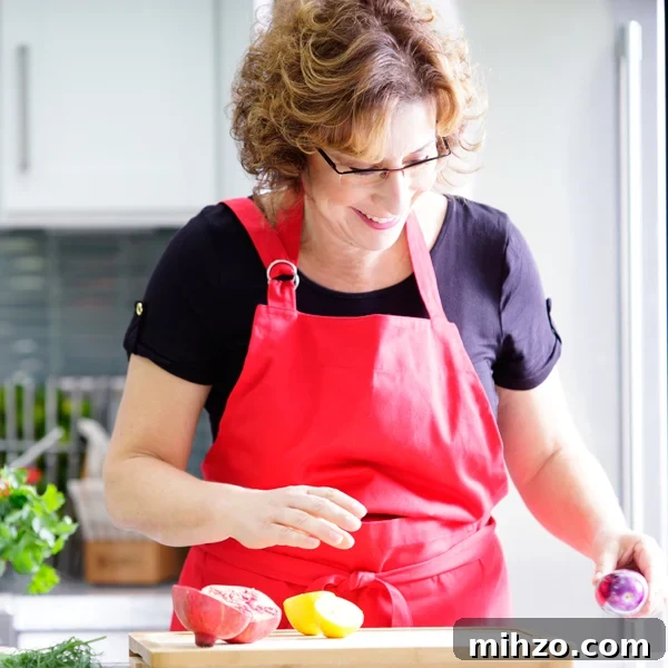 Crisp Pickled Red Onions: Quick Tangy Recipe for Sandwiches & Salads 12 Beth Lee in red apron looking at vegetables on cutting board
