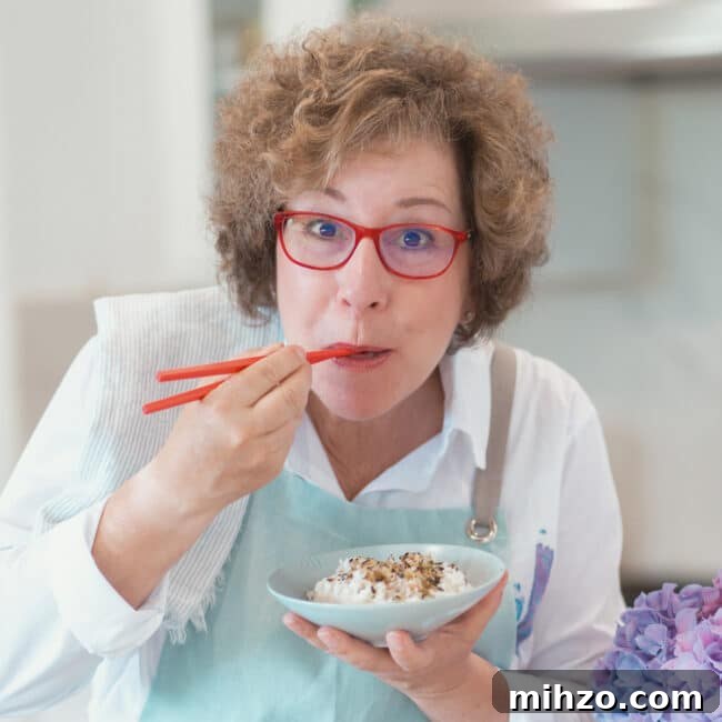 Crisp Pickled Red Onions: Quick Tangy Recipe for Sandwiches & Salads 13 Beth Lee holding red chopsticks and eating rice out of blue bowl.