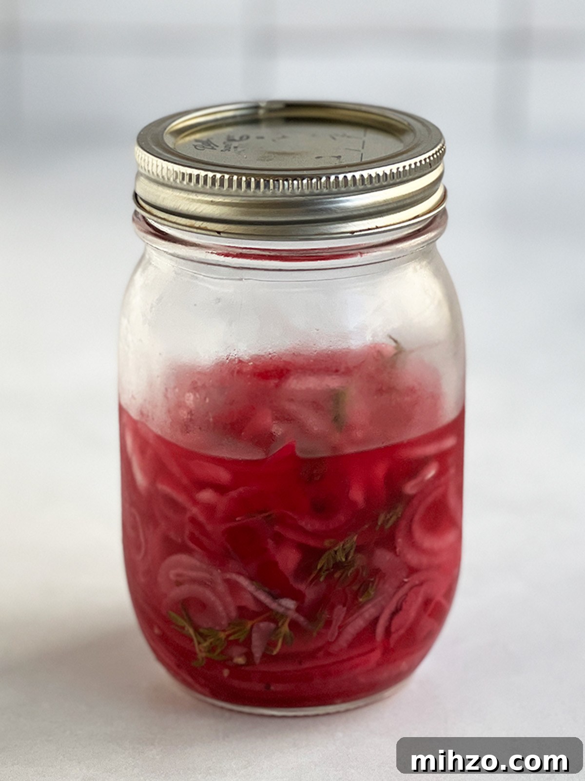 Crisp Pickled Red Onions: Quick Tangy Recipe for Sandwiches & Salads 6 Pickled red onions ready to eat in a larger jar that looks about ⅔ full.