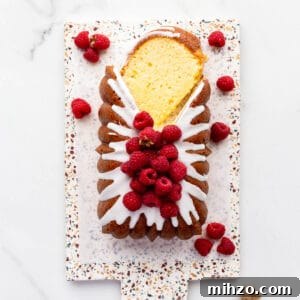 Moist Lemon Loaf Cake Recipe with Zesty Glaze 18 Lemon loaf cake topped with lemon icing and fresh raspberries being sliced to serve it