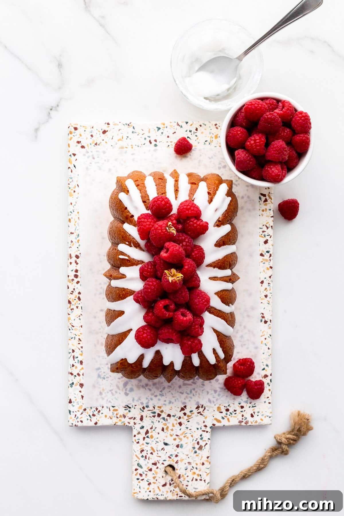 Moist Lemon Loaf Cake Recipe with Zesty Glaze 10 Lemon drizzle cake topped with icing and fresh raspberries.