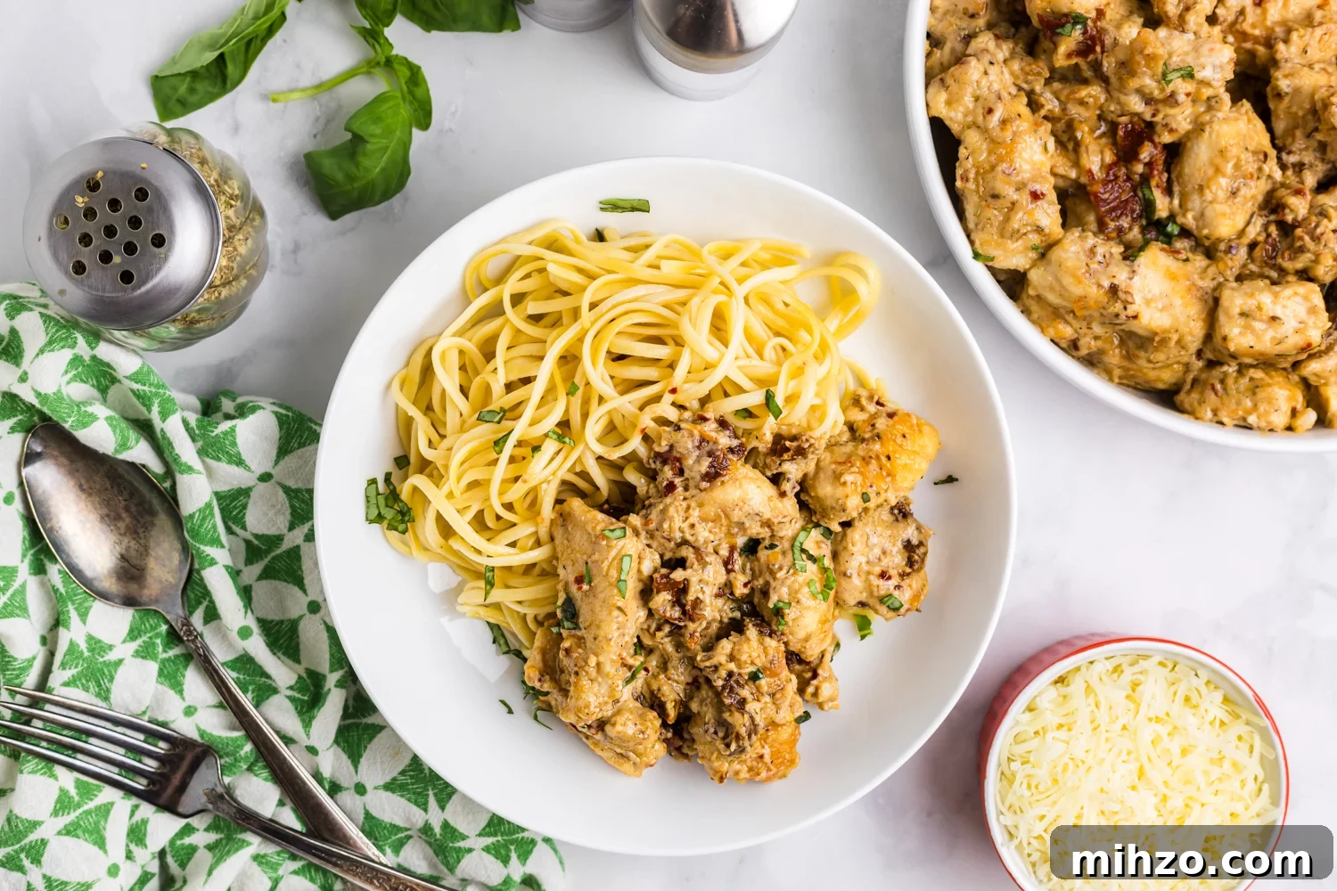 Overhead view of a bowl of pasta topped with creamy sun-dried tomato chicken