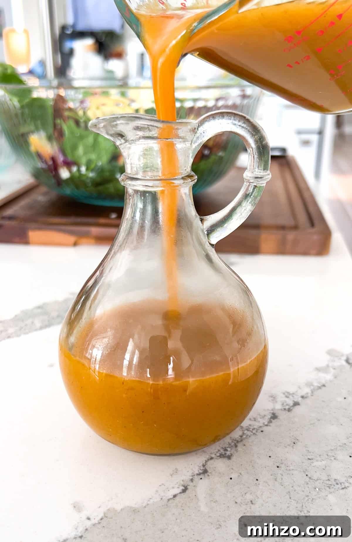 Autumn Apple Salad with Candied Pecans and Maple Vinaigrette 5 Pouring maple pumpkin dressing into bottle.