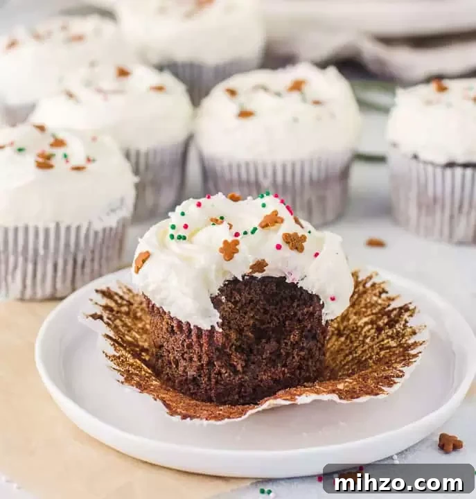 cupcake with a bite taken out of it on a plate with more gingerbread cupcakes in the background