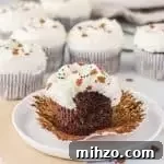 cupcake with a bite taken out of it on a plate with more gingerbread cupcakes in the background