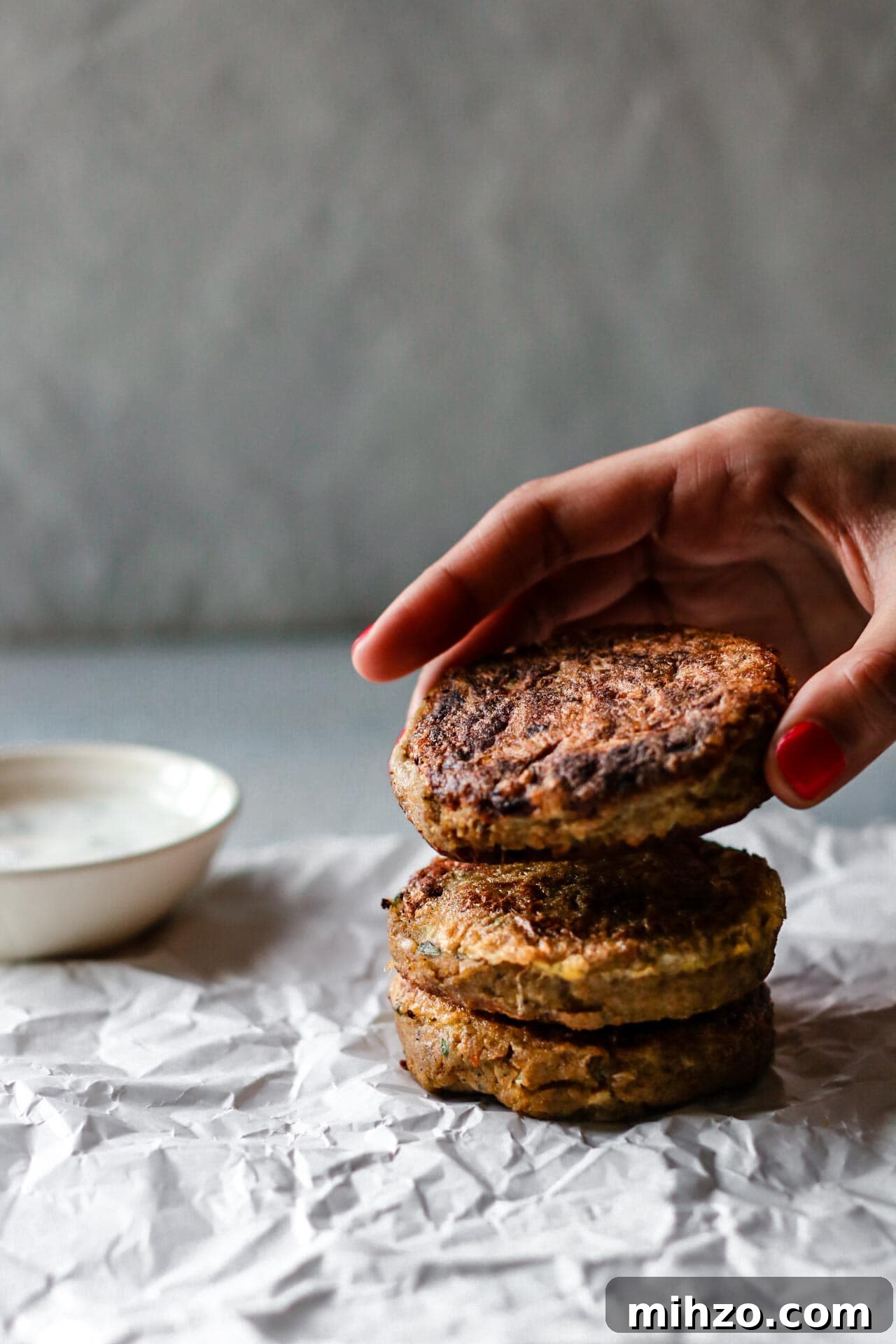 Stacking Shami Kebab with a bowl of raita in the background.