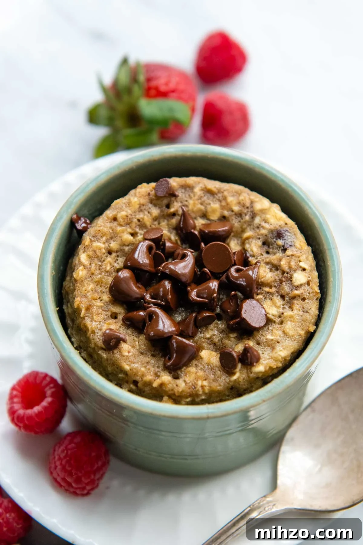 Fluffy 2-Minute Oatmeal Mug Cake — No Flour Mug Cake 6 overhead shot of mug cake in a green dish with berries around.