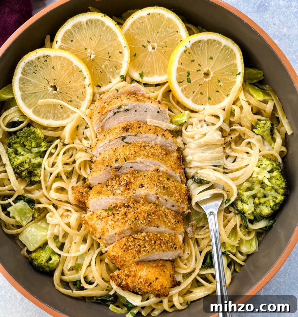 Lemon Garlic Chicken Pasta with Creamy Parmesan Sauce 2 lemon chicken pasta in a pan with fresh lemons, spinach, and broccoli