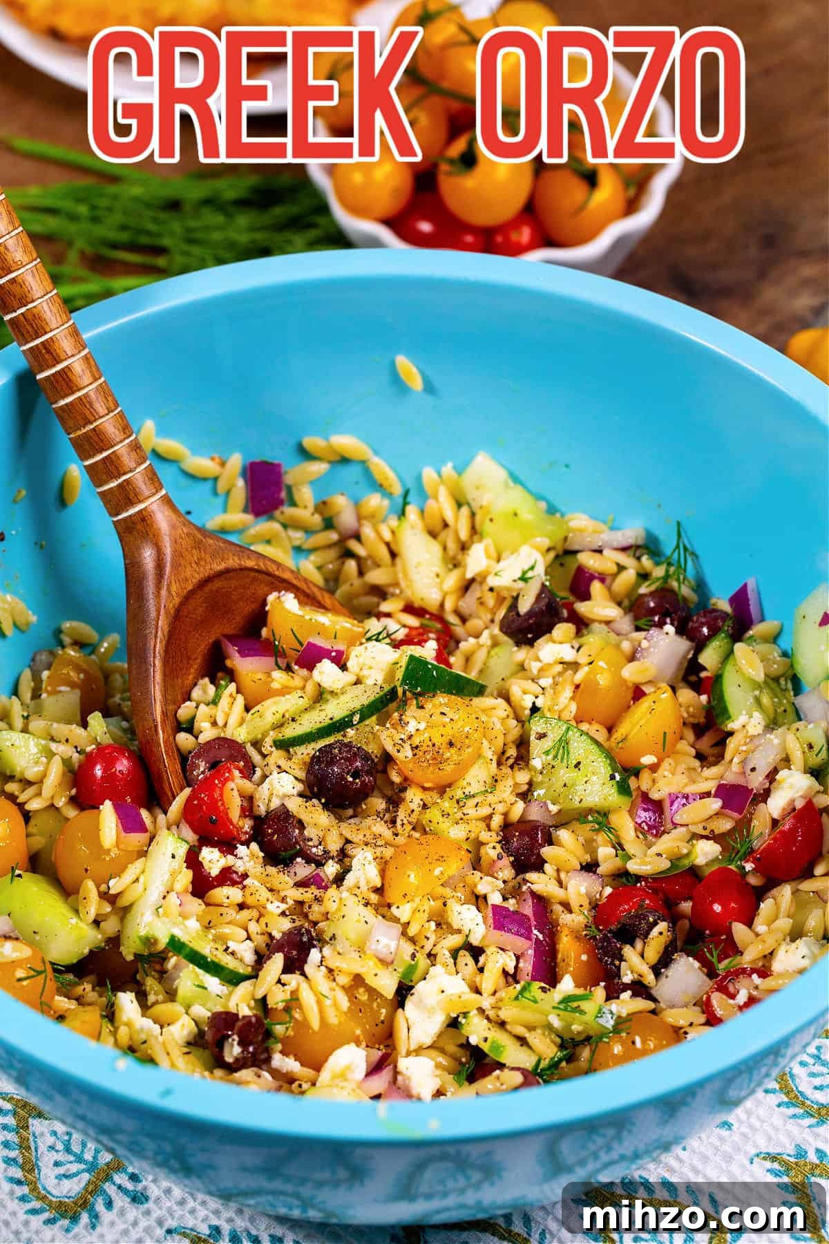 Orzo salad being stirred with wooden spoon.