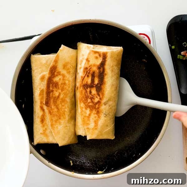 High-Protein Breakfast Burrito with Crispy Potato Filling 12 Toasting the breakfast burritos in the skillet.
