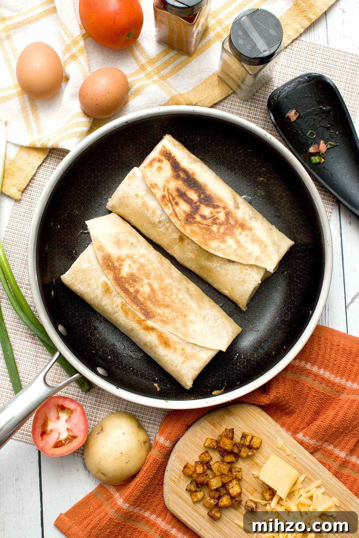 High-Protein Breakfast Burrito with Crispy Potato Filling 13 Two toasted high protein breakfast burritos in a skillet.