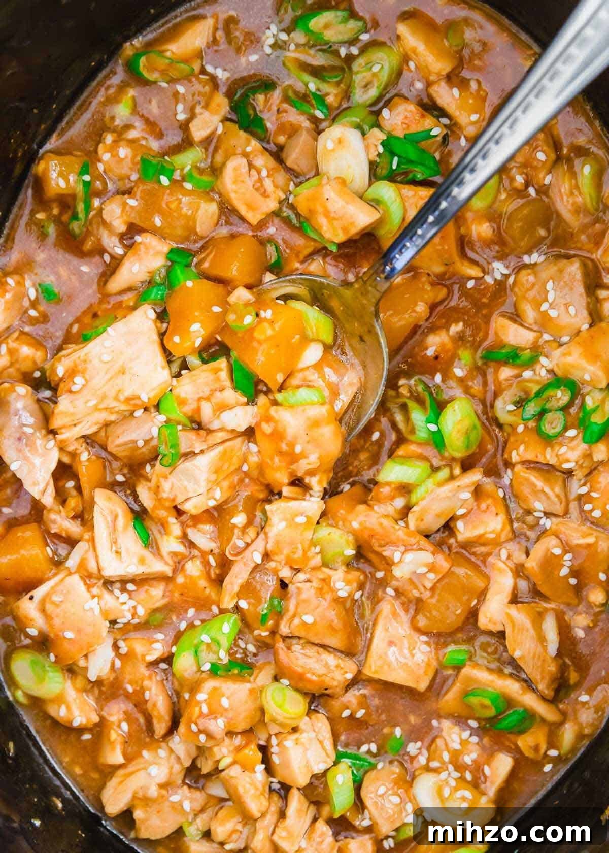 Slow cooker honey garlic chicken in the slow cooker insert with ladle.