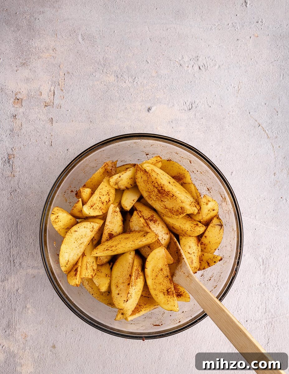 Crispy Oven-Baked Potato Wedges with Smoky Chipotle Sauce 13 a bowl of cut potatoes coated in olive oil and taco seasoning.