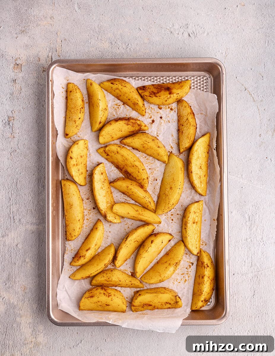 Crispy Oven-Baked Potato Wedges with Smoky Chipotle Sauce 14 seasoned potato wedges on a sheet pan.