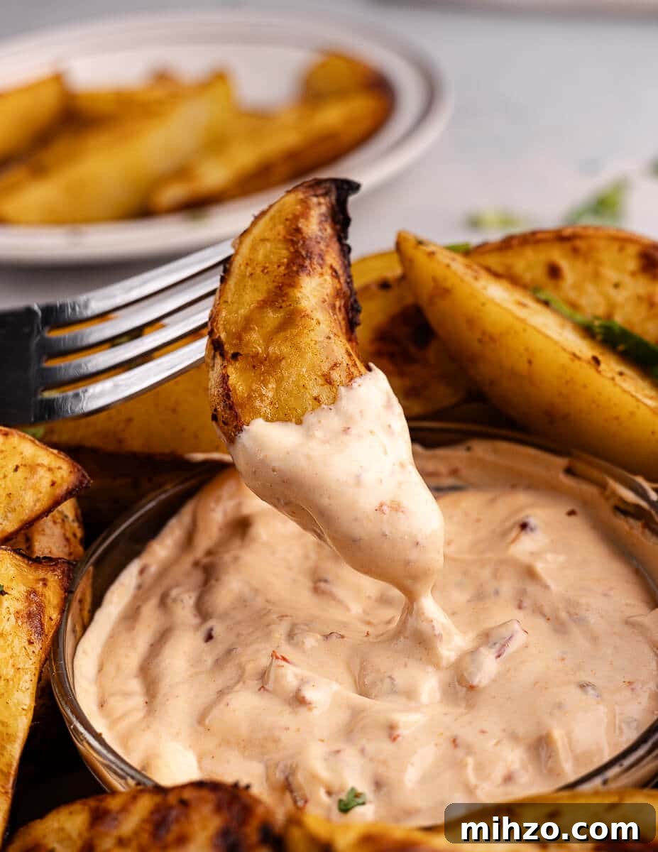 Crispy Oven-Baked Potato Wedges with Smoky Chipotle Sauce 4 dipping a potato wedge in chipotle sauce.