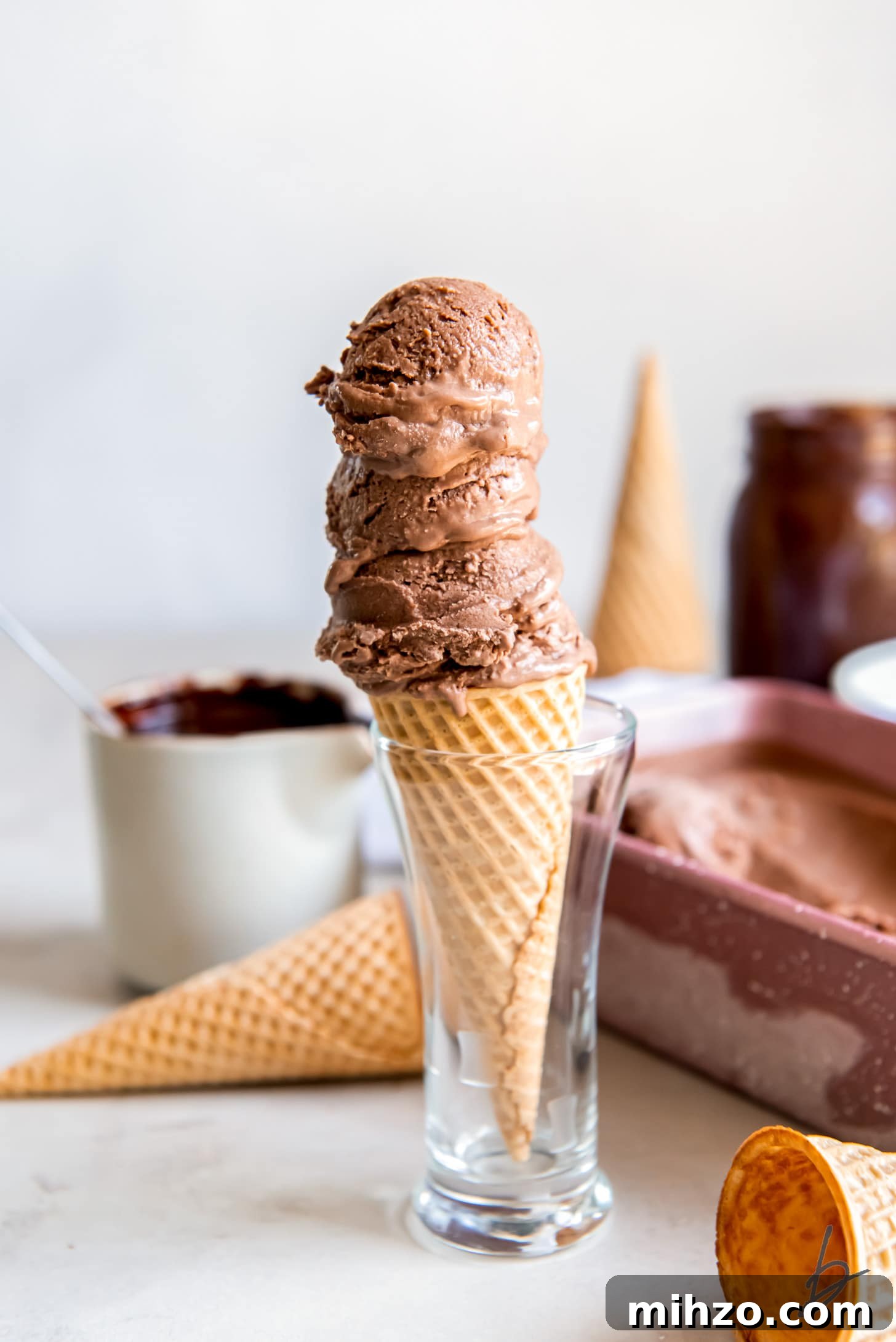 three scoops of chocolate ice cream on a sugar cone in a small glass