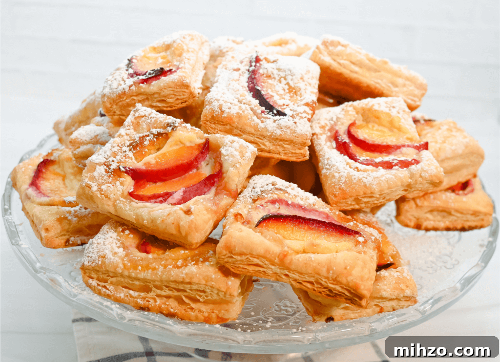 A clear cake plate full of mini tarts dusted in powdered sugar