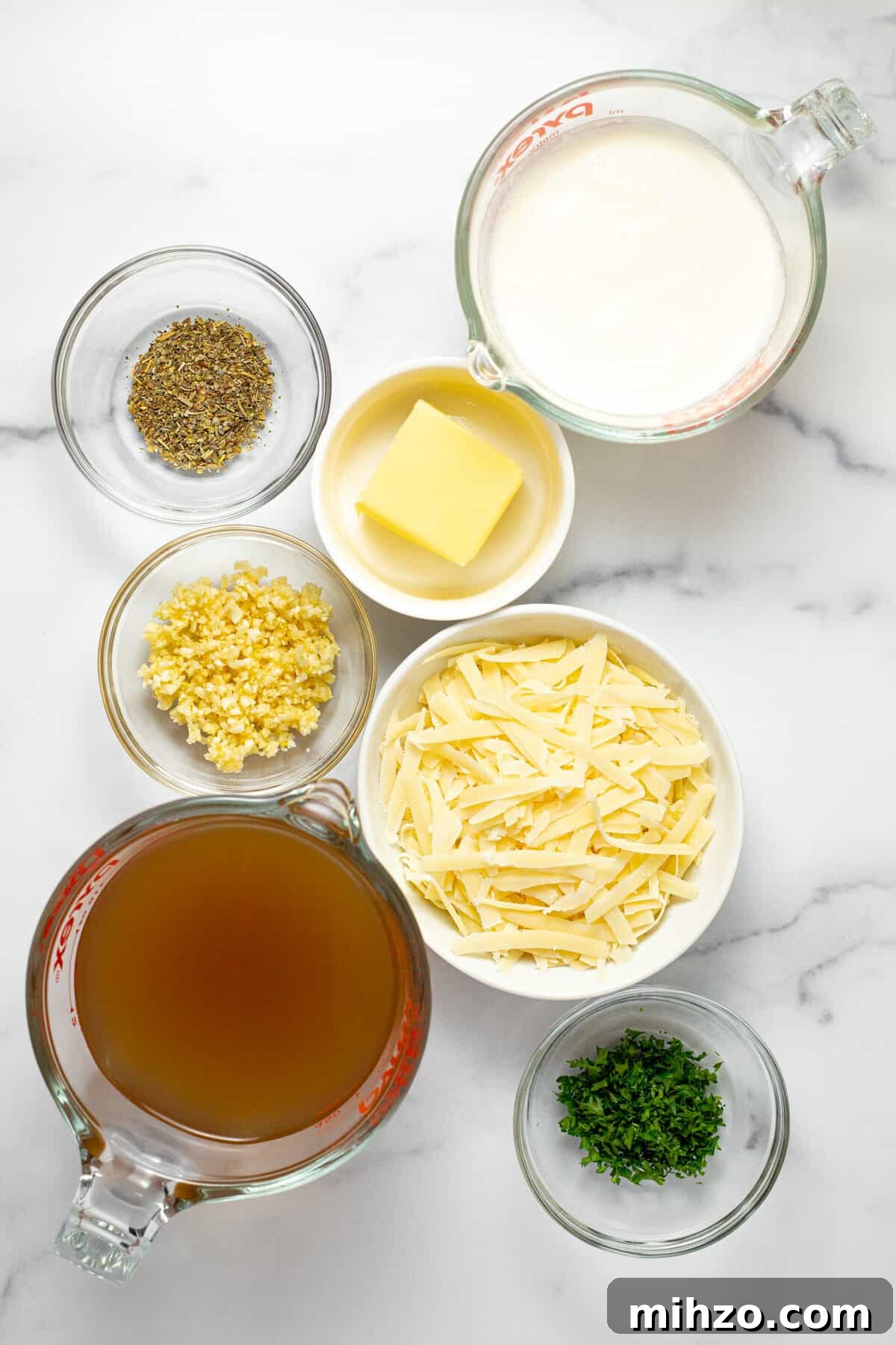 15-Minute Garlic Parmesan Sauce Recipe for Quick Dinners 3 White marble counter top with bowls of ingredients to make Parmesan garlic sauce