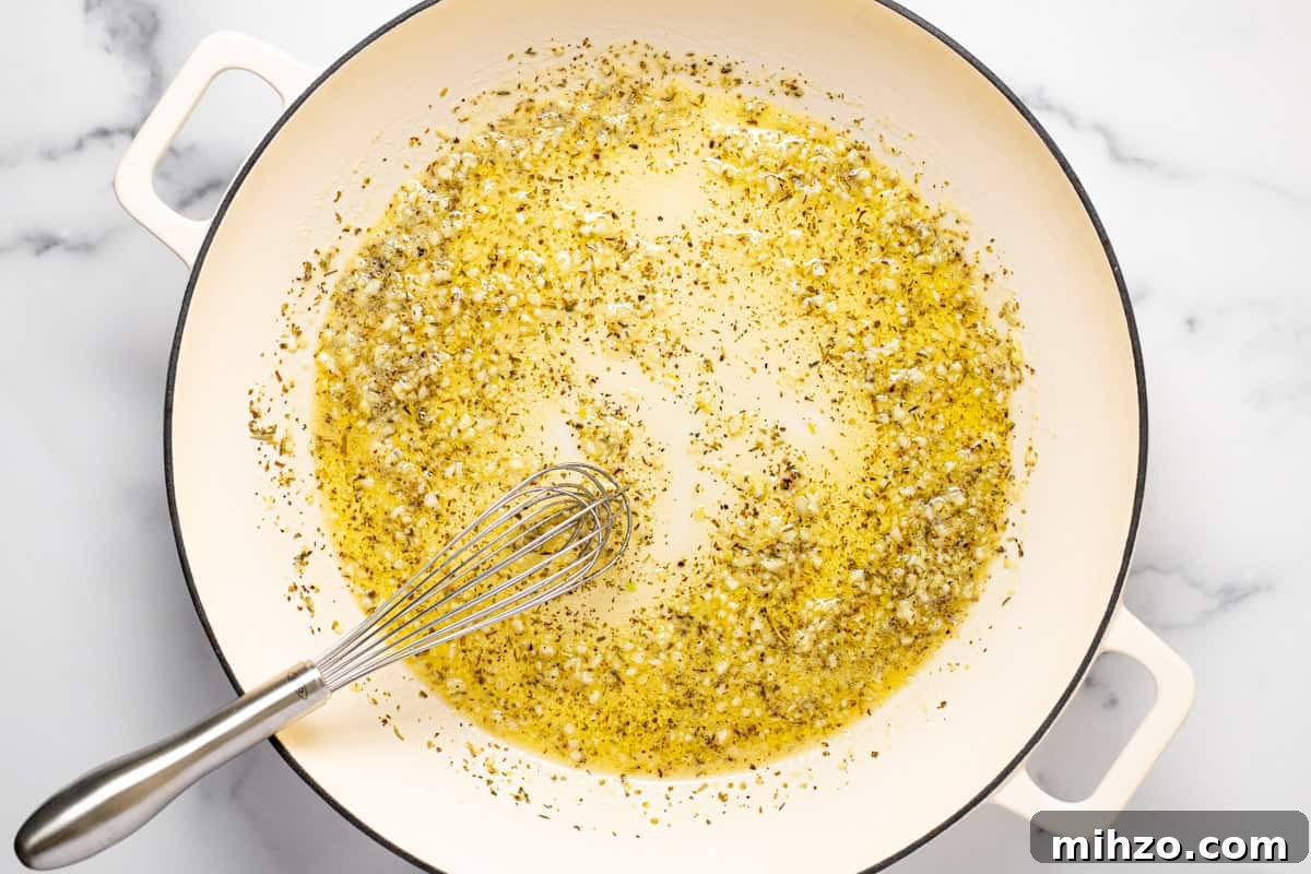 15-Minute Garlic Parmesan Sauce Recipe for Quick Dinners 4 Large white sauté pan filled with sautéed garlic and dried herbs