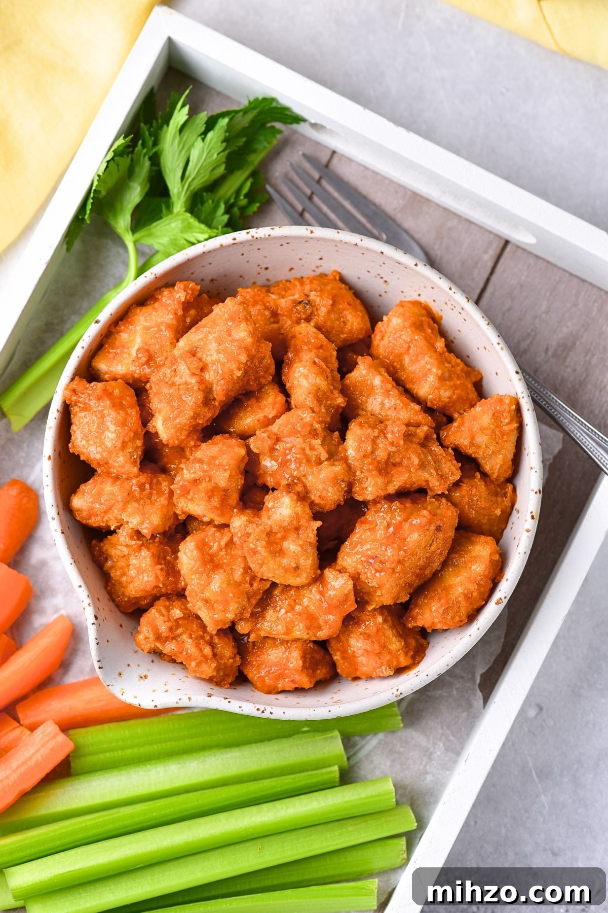 Air Fryer Buffalo Chicken Recipe (Gluten-Free, Dairy-Free) A bowl of buffalo chicken bites and carrot sticks and celery sticks.