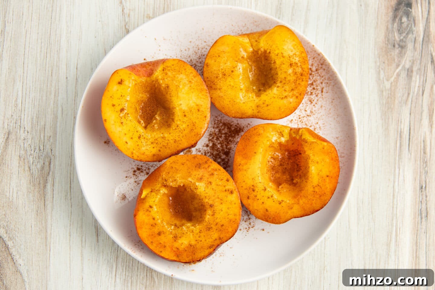 Crispy Air Fryer Peaches with Honey-Brown Sugar Glaze 5 Picture of 4 peach halves seasoned with honey and cinnamon.