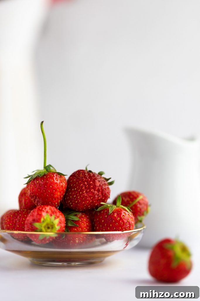 Strawberry Simple Syrup Recipe for Drinks and Desserts 3 A small glass dish holding a pile of fresh strawberries.