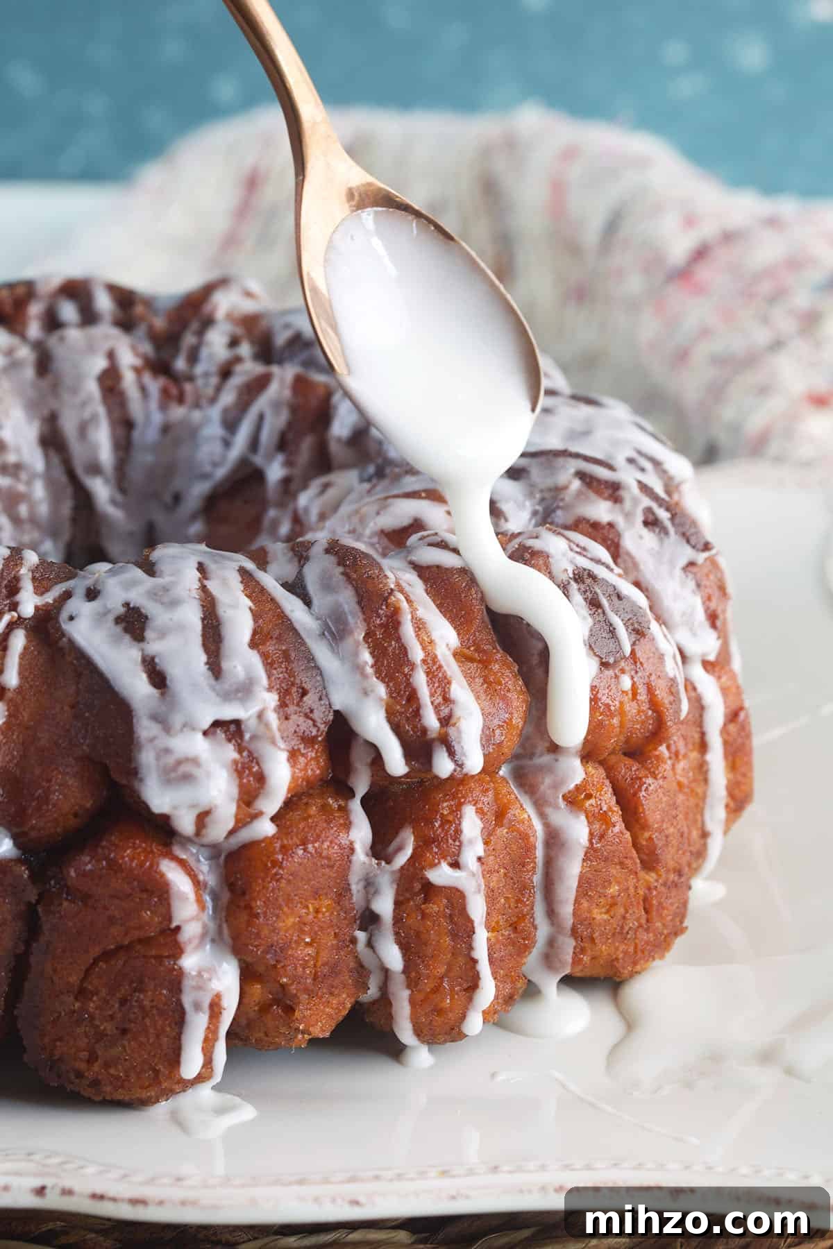 Perfect Sticky Monkey Bread Recipe for Warm Gatherings 4 Icing is being drizzled on the monkey bread with a spoon.