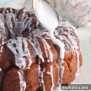 Perfect Sticky Monkey Bread Recipe for Warm Gatherings 6 Icing is being drizzled on the monkey bread with a spoon.