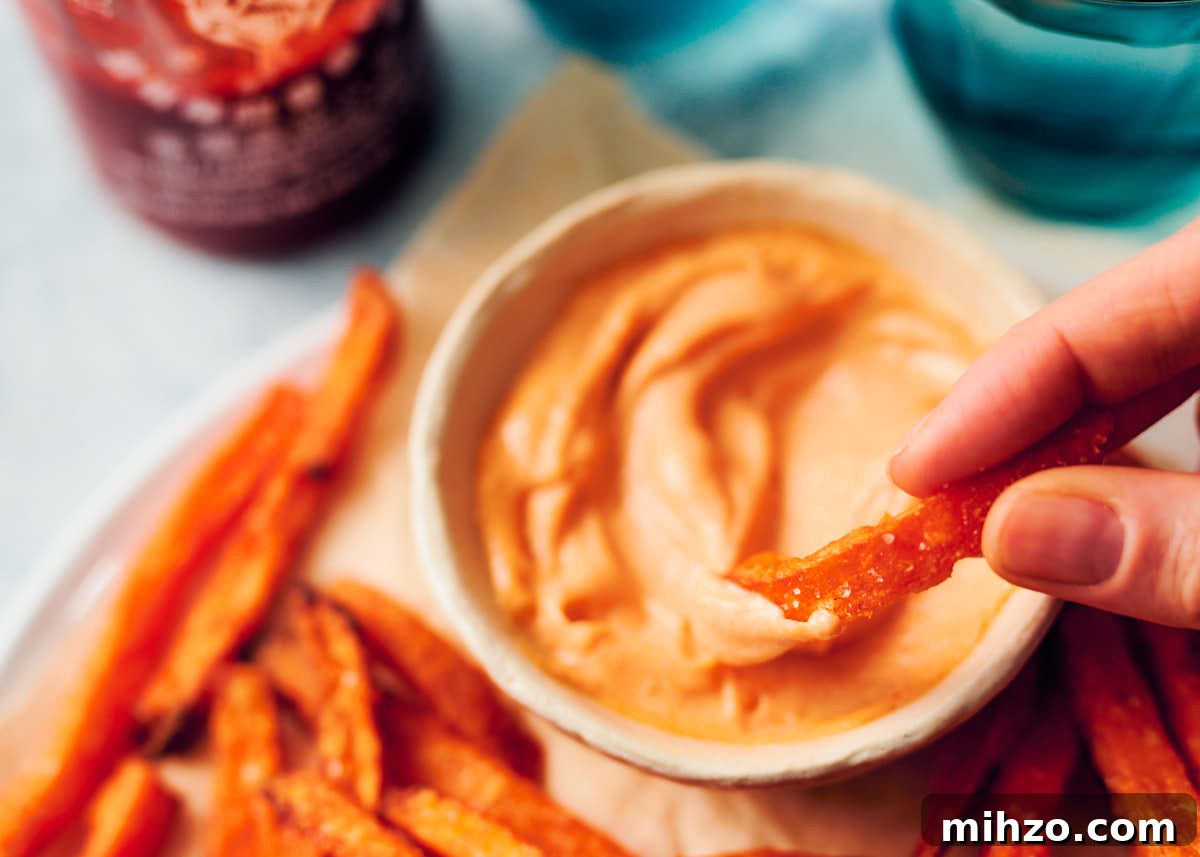 Quick Sriracha Aioli Recipe with 3 Ingredients 9 A sweet potato fry being dipped into a bowl of sriracha aioli.