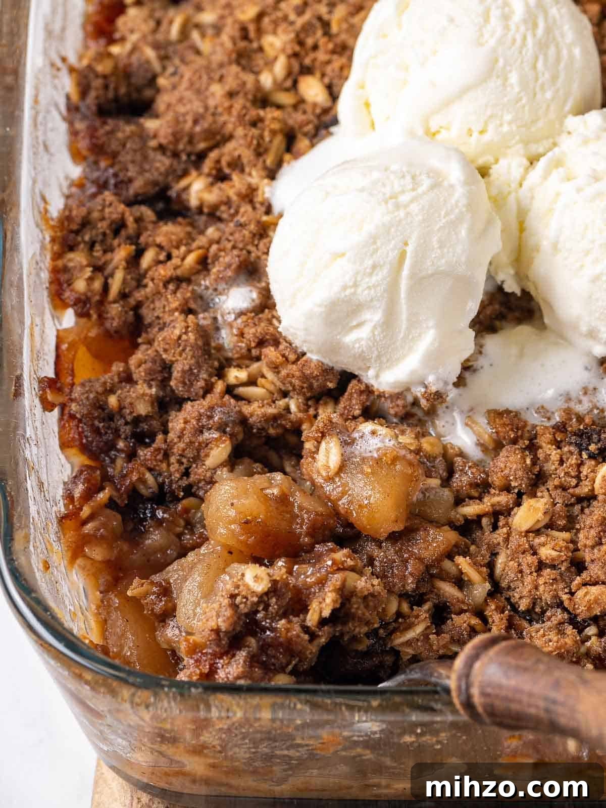 apple crisp in baking dish with ice cream on top.