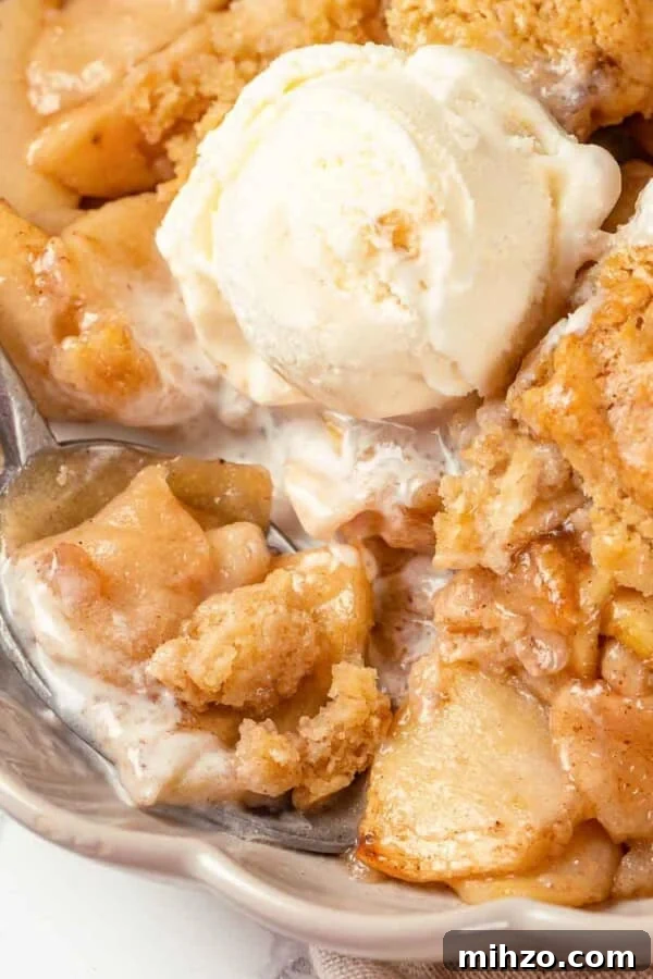A scoop of vanilla ice cream melting on warm apple cobbler.