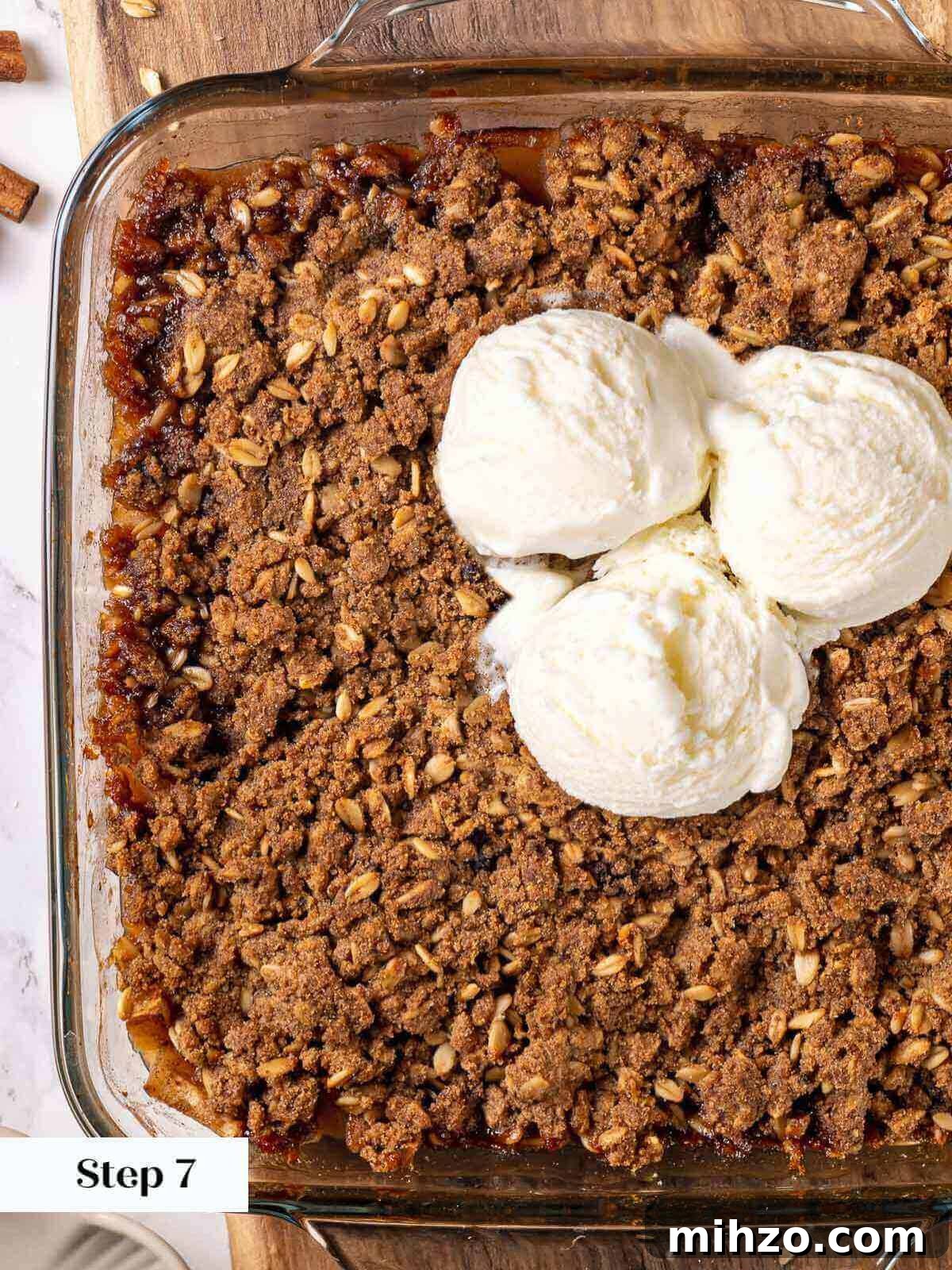 apple crisp in baking dish with ice cream on top.