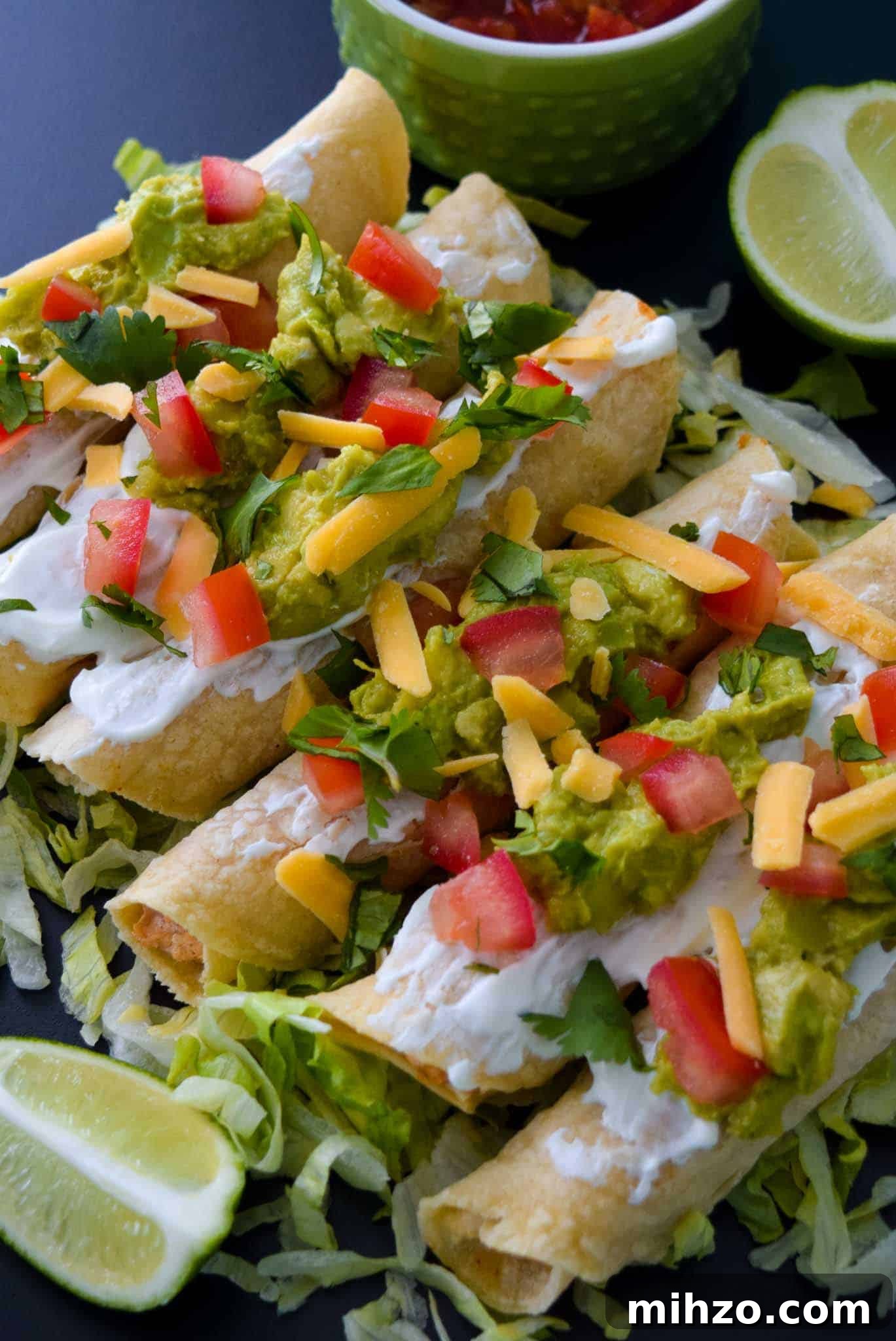 Crispy Baked Chicken Taquitos with Avocado Crema 3 Baked Chicken Taquitos with toppings ready to be served close up