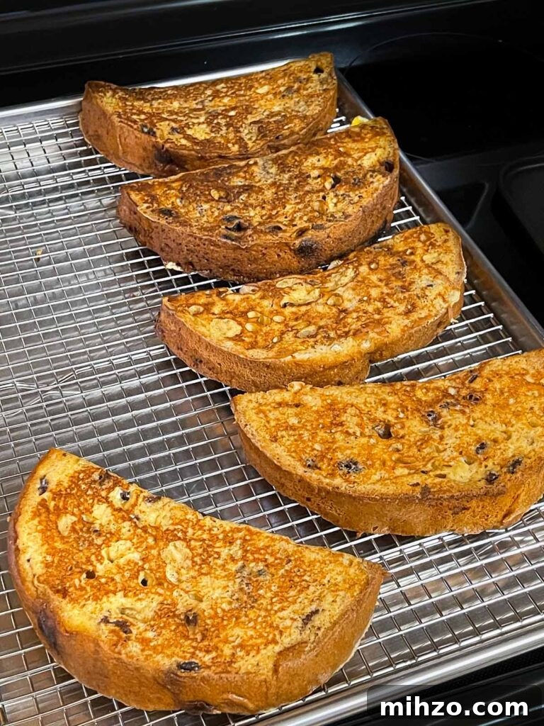 Decadent Panettone French Toast Recipe for Brunch 8 Cooked panettone french toast on a wire rack lined baking sheet.