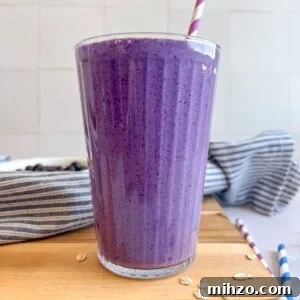 High-Protein Blueberry Smoothie Recipe for Muscle Recovery 2 Blueberry muffin smoothie in a glass with a purple striped straw