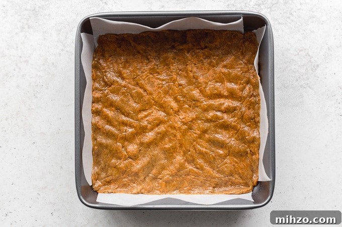 Carrot cake cookie dough pressed into a square pan.