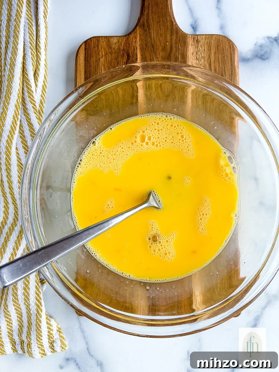 Sourdough Breakfast Sandwich Ideas for Quick Morning Meals 5 Fork in a clear glass mixing bowl with yellow liquid.