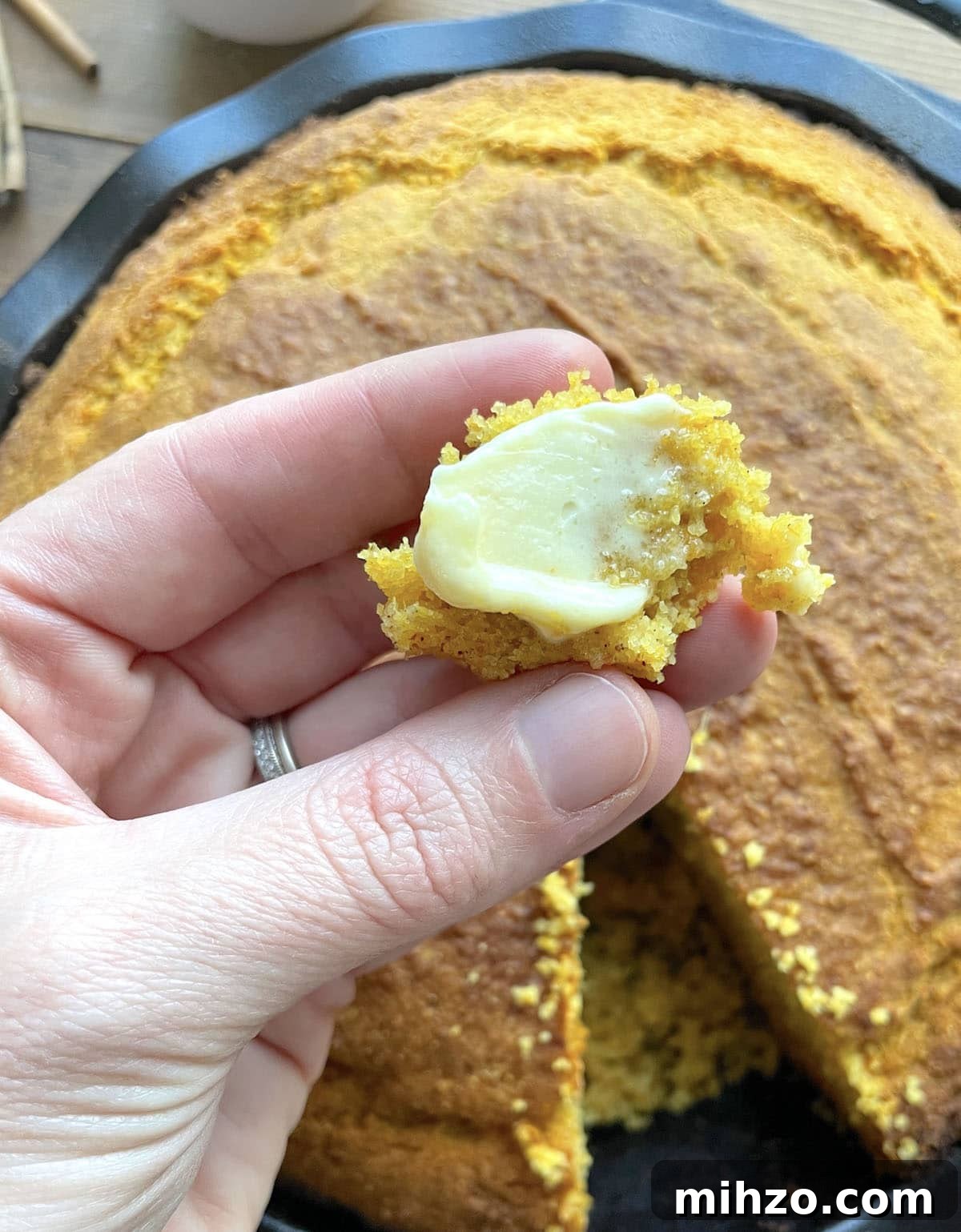Whipped Honey Butter Recipe: Smooth, Spreadable & Quick 11 A hand holding sweet potato cornbread with a smear of honey butter on it.