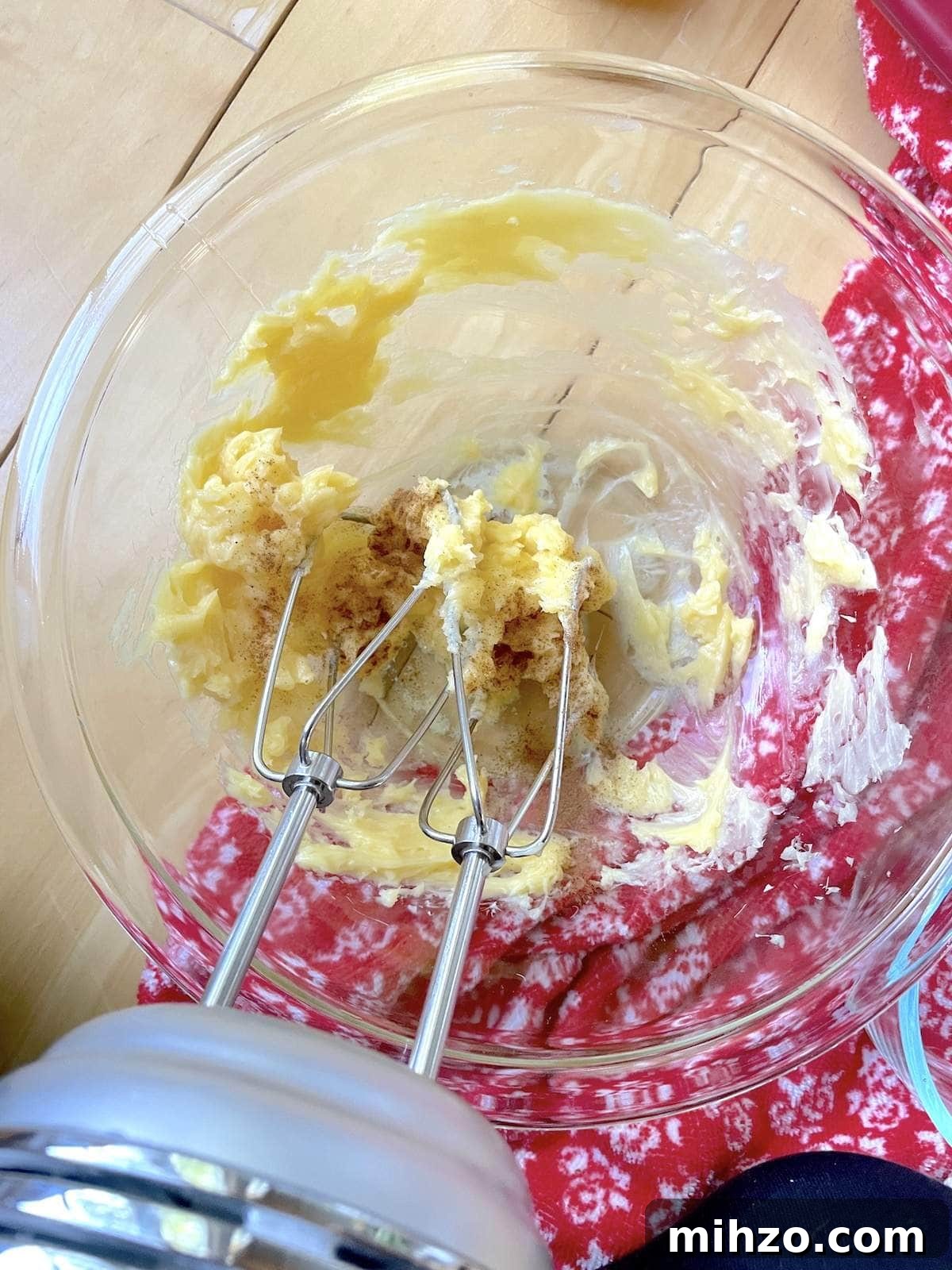 Whipped Honey Butter Recipe: Smooth, Spreadable & Quick 7 A small bowl of honey butter being whipped with an electric mixer, with cinnamon and vanilla extract being added to it.