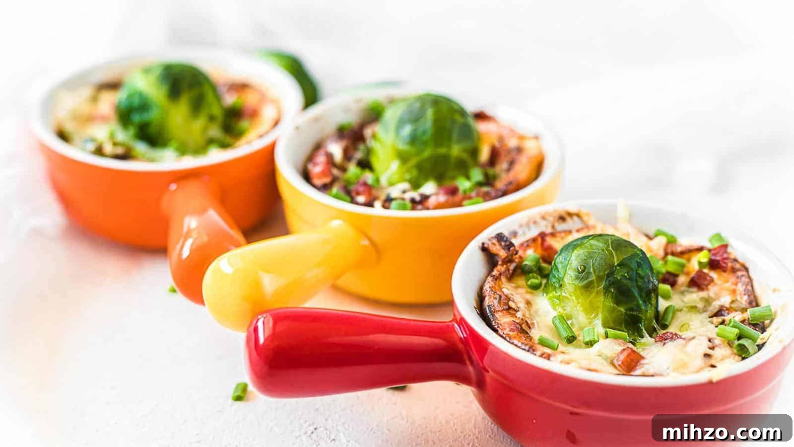 24 Brussels Sprouts Recipes That Even Non-Veggies Will Love 2 Three colorful ramekins filled with a baked dish topped with a Brussels sprout and chopped chives, arranged in a row on a light surface.