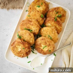Crispy Potato Fritters Recipe — Golden Pan-Fried Latkes 10 Overhead shot of potato fritters on a white rectangle plate garnished with fresh parsley.
